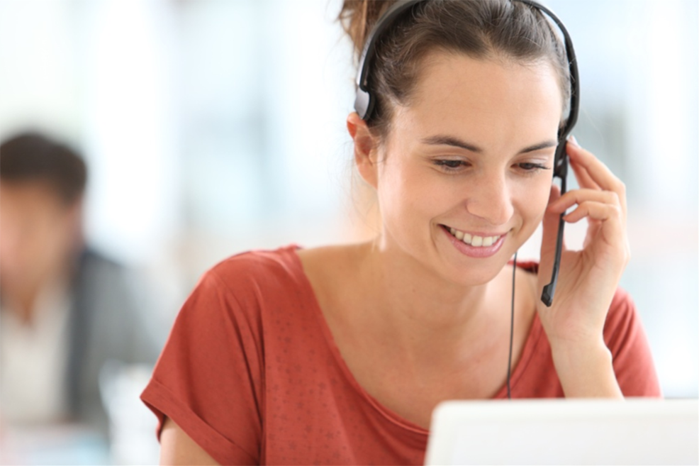 Successful, smiling call center worker with headset working at an office.